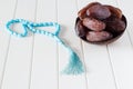 Fresh dates Medjool in wooden coconut bowl and blue rosary. Royalty Free Stock Photo