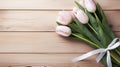 fresh delicate pink tulips with a ribbon on a light, wooden background. Congratulations on Valentine\'s Day,