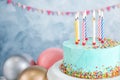 Fresh delicious birthday cake with candles near balloons on color background.