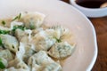 Fresh, delicious boiled garlic chives dumplings, jiaozi in white plate on wooden table background