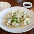 Fresh, delicious boiled garlic chives dumplings, jiaozi in white plate on wooden table background