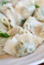 Fresh, delicious boiled garlic chives dumplings, jiaozi in white plate on wooden table background