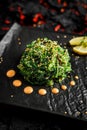 Fresh delicious Chukka seaweed Wakame salad ina black plate on a black stone background with limon and sauce Royalty Free Stock Photo