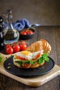 Fresh and delicious Croassan sandwich with green salad, tomatoes, cheese and scrambled eggs on a wooden board and a Royalty Free Stock Photo