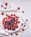 Fresh delicious homemade cake with strawberries and blueberries In the form of heart In pink white napkins on rustic wooden b