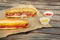 Fresh delicious hot dogs and sauces on wooden surface