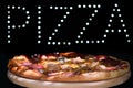 Fresh tasty Italian pizza on a black background with a spectacular light inscription `pizza`