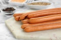 Fresh delicious sausages on white marble table