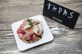 Fresh delicious Spanish tapas with hamon with fresh herbs and strawberries with poster TAPAS on the wooden background . Great bac