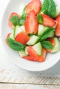 Fresh Detox Summer Salad with Strawberries Green Mint Leaves in White Ceramic Bowl. Plank Wood Table. Top View