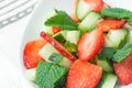 Fresh Detox Summer Spring Salad with Strawberries Green Mint Leaves in White Ceramic Bowl on Cotton Napkin. Plank Wood Table