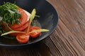 Fresh diet salad with tomatoes, cherry tomatoes, mozzarella, arugula, seasoned with olive oil in a black plate. Royalty Free Stock Photo