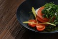 Fresh diet salad with tomatoes, cherry tomatoes, mozzarella, arugula, seasoned with olive oil in a black plate. Royalty Free Stock Photo