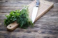 Fresh dill and parsley on a cutting board with knife on wooden table