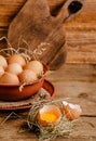 Fresh domestic eggs and broken eggshell with yolk on rustic wooden background Royalty Free Stock Photo