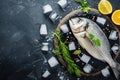 Fresh Dorado with lemon and marinade on a black cutting board with pieces of ice