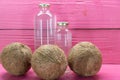 Fresh dried coconuts and bottles on pink colored wooden background Royalty Free Stock Photo