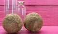 Fresh dried coconuts and bottles on pink colored wooden background Royalty Free Stock Photo