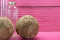 Fresh dried coconuts and bottles on pink colored wooden background Royalty Free Stock Photo