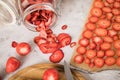 Fresh and dried strawberries from dehydrator for long term prepper pantry with knife, wooden cutting board and glass jar on light