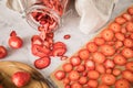 Fresh and dried strawberries from dehydrator for long term prepper pantry with knife, wooden cutting board and glass jar on light