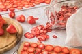 Fresh and dried strawberries from dehydrator for long term prepper pantry with knife, wooden cutting board and glass jar on light