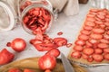 Fresh and dried strawberries from dehydrator for long term prepper pantry with knife, wooden cutting board and glass jar on light