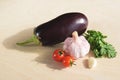 Fresh eggplant, a head of garlic, branch of cherry tomatoes and and a sprig of fresh cilantro on wooden board Royalty Free Stock Photo