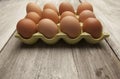 Fresh eggs in a green ceramic holder on rustic background