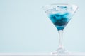Fresh exotic alcohol drink with blue liquor curacao and ice cubes in misted wineglass on elegant blue pastel color background. Royalty Free Stock Photo