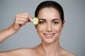 Fresh-faced beauty. Studio shot of a beautiful mid adult woman holding a slice of cucumber to her face. Royalty Free Stock Photo