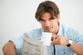 Fresh faced and ready for the day. Portrait of a sexy young man drinking a cup of coffee while reading the newspaper. Royalty Free Stock Photo