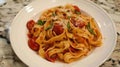 Fresh fettuccine pasta with flour dusting, basil leaves, and tomato on a wooden board Royalty Free Stock Photo