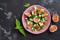 Fresh fig salad with mozzarella and greens on a dark grunge stone background. Top view, copy space. Royalty Free Stock Photo