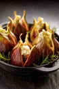 Fresh figs stuffed with gorgonzola cheese, pine nuts and herbs in a black dish on a dark, stone ground, close up. Royalty Free Stock Photo