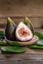 Fresh figs on wooden plate, with fig leaves, on wooden background. vertical format Royalty Free Stock Photo