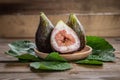 Fresh figs on wooden plate, with fig leaves, on wooden background Royalty Free Stock Photo