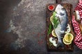 Fresh fish dorado with ingredients for cooking on wooden board. Raw sea bream or dorada fish on dark vintage metal background. Die Royalty Free Stock Photo