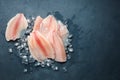 Fresh fish fillet of sea bass in ice on a dark slate background.