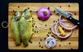 Fresh cut raw river Catla fish, cleaned with turmeric, prepared for baking in the oven with herbs and seasoning on a wooden board.