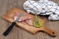 Knife on raw red mullet fillets laid on a cutting board with a slice of lemon and rosemary close-up on a wooden background