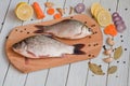 Fresh fish, lemon and other ingredients on the kitchen board Royalty Free Stock Photo