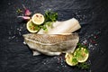 Fresh fish, raw cod fillet with addition of herbs and lemon slices on black stone background Royalty Free Stock Photo