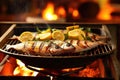 fresh fish sizzling on a boat grill with lemon slices