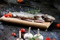 Fresh fish on a vintage black, burnt table. Wooden table. Fish with vegetables, salt, oil, herbs. Concept of cooking. Healthy and