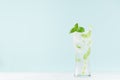 Fresh fitness mineral water with green mint leaf, ice cubes, tonic, striped straw in elegant glass on white wood table, mint color Royalty Free Stock Photo