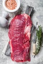 Fresh Flank or flap raw beef steak on wooden board with herbs. Gray background. Top view