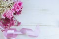 A fresh floral arrangement of soft pink roses and dried flowers with beautiful satin ribbon on rustic white washed wooden table. Royalty Free Stock Photo