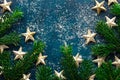 Fresh fluffy fir tree branches decorative golden star ornaments snow powder on dark blue turquoise backdrop. Christmas New Year