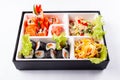 Fresh food portion in japanese bento box with salad, main course. Sushi roll with vegetables. Vegetarian dish.